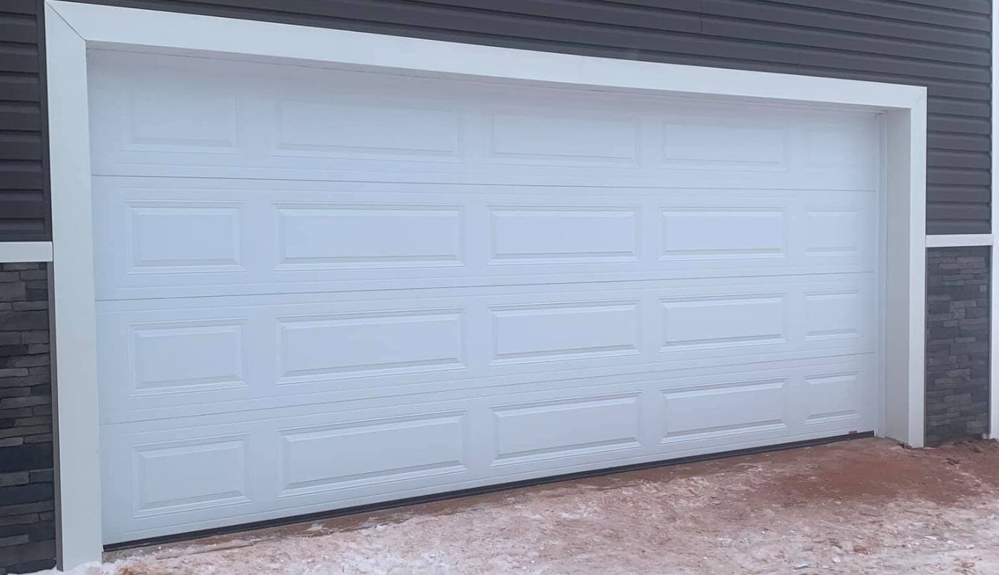 A white garage door complemented by white trim, showcasing a simple and elegant aesthetic.