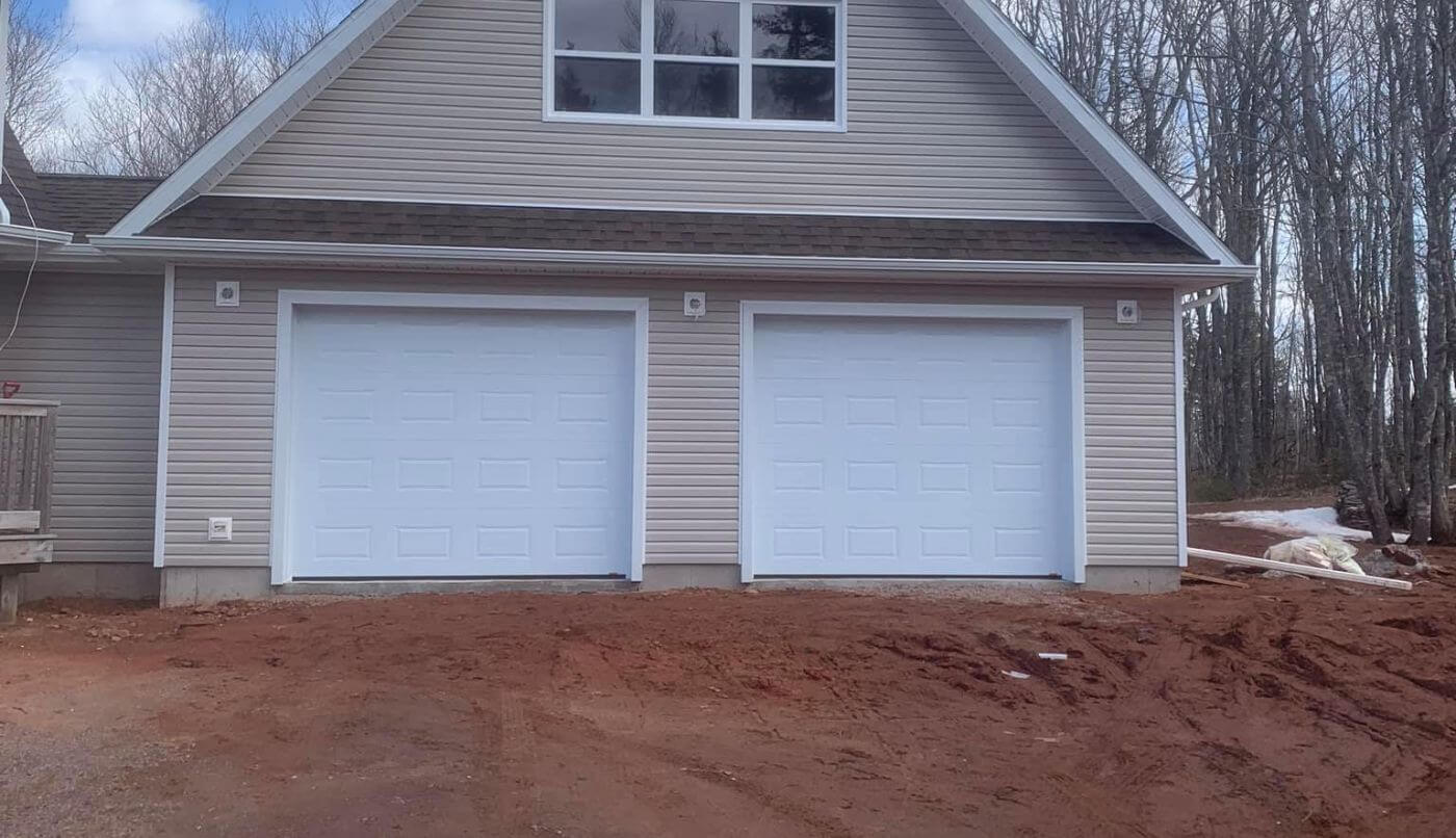 A garage with two white doors and a pitched roof, showcasing a clean and simple architectural design.
