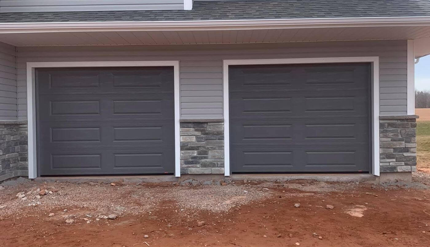 Two gray garage doors featuring white trim, showcasing a modern and clean aesthetic for residential architecture.